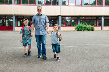 Back to school. Happy dad escorts his sons schoolchildren to school. Parental care for children.