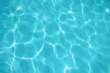 ripples of water from a swimming pool with a blue background with the sun reflecting in the water
