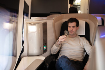 Male businessman holding glass of champagne on first class busines flight