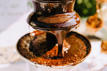 Hot milk melted chocolate pours over the fountain close-up. Food photography.