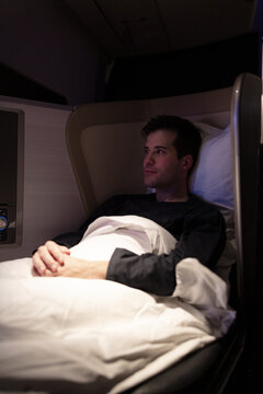 Airline passenger resting in the seat turned to a bed in the first class cabin.