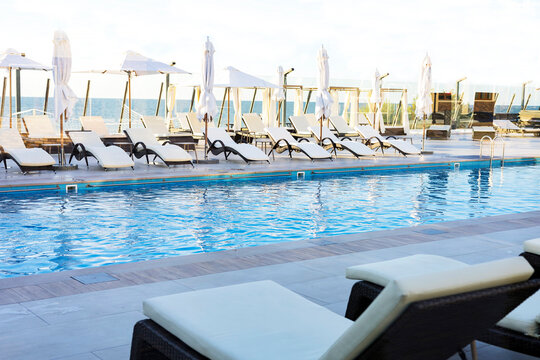 Umbrella and deck chair around outdoor swimming pool in hotel resort nearly sea beach ocean for travel vacation.