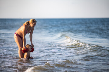 Mom throws her son up over the sea on summer vacation under the warm sun