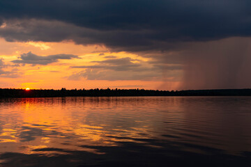 Dramatic summer sunset on the lake. Thunderclouds and rain.

