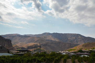 Small scale vineyard and houses against the backdrop of mountains at village of winemakers Areni Vayots Dzor Province, Armenia. Grape agriculture and production of high-quality varieties of wine