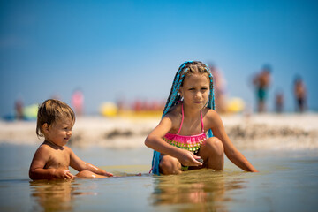 Older sister playing with younger brother aground near the shore on summer vacation