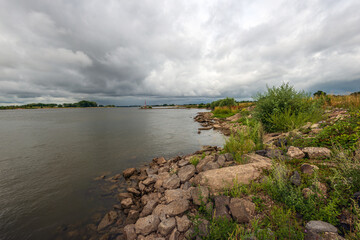 Many stones on the bank of the Dutch river Waal. The photo was taken on a cloudy day in the summer season near the village of Herwijnen in the province of Gelderland.