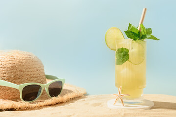 Freshness mojito cocktail on beach, straw hat and eyeglasses in sunny shadow. Concept of summer holiday vacation on beach. Close up. Copy space. Banner.