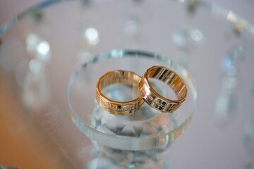 Wedding rings for weddings lie on a mirror reflecting surface.