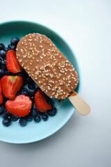 Strawberries, blueberries and chocolate ice cream in blue plates on a light background. Natural ice cream close-up. Fresh organic berries and fruits. Traditional milk product
