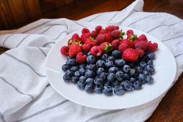 Plate with delicious raspberry strawberries and blueberries on a light background. Fresh organic berries and fruits. Farm ecological product. Without GMO. Fresh vitamins
