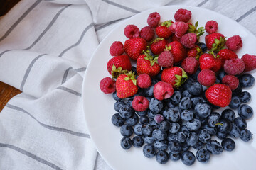 Plate with delicious raspberry strawberries and blueberries on a light background. Fresh organic berries and fruits. Farm ecological product. Without GMO. Fresh vitamins