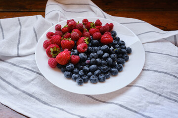Plate with delicious raspberry strawberries and blueberries on a light background. Fresh organic berries and fruits. Farm ecological product. Without GMO. Fresh vitamins