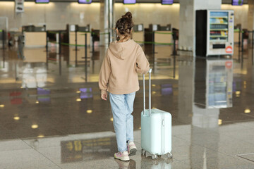 Traveling with children. cute teenage girl walking together with travel suitcase in airport. cute child girl goes on trip abroad on weekends. back view