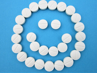        Smiling face made of white round pills on blue background  