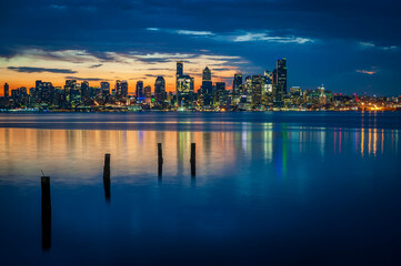 Fototapeta na wymiar Seattle Skyline During the Morning Blue Hour Seen From West Seattle. Dynamic view of the Seattle cityscape just before dawn with Elliott Bay in the foreground and the waterfront in the distance. 