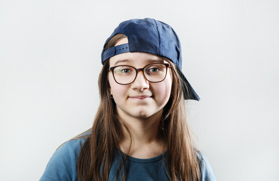 Portrait of teenage girl in glasses and baseball cap.