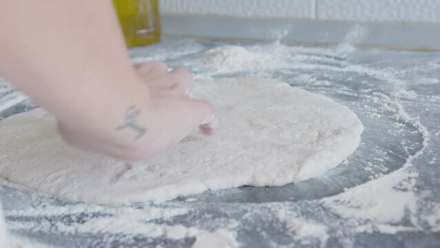 Cook rolls out the dough for pizza with a rolling pin. The cook rolls out the dough, chef is baking, bakery products, making the dough