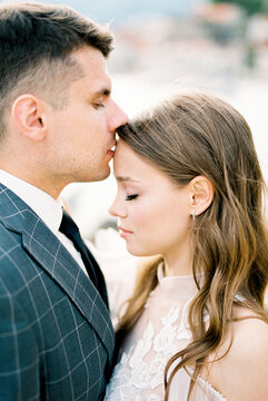Groom kisses bride on the forehead. Portrait. Profile