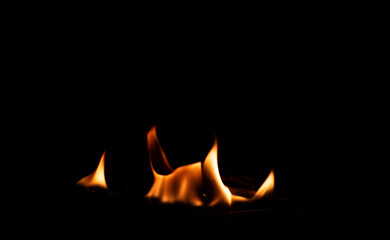 Flame in the fireplace, yellow tongues of fire. Black background. Firewood burning. Heating the...