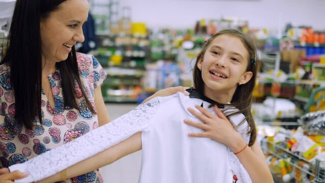 Mom and daughter pick up a blouse in the supermarket for school uniforms.