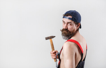 Portrait of a bearded man in a baseball cap with a hammer in his hand. Copy space for your text.