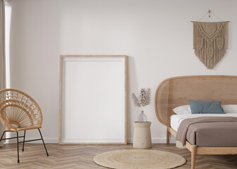 Empty vertical picture frame standing on parquet floor in modern bedroom. Mock up interior in boho style. Free space for picture or poster. Bed, macrame, rattan armchair, pampas grass. 3D rendering.