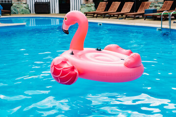 an inflatable flamingo swims in the pool. the concept of summer holidays.