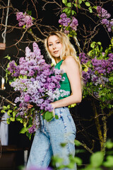 a cute woman in a green top and jeans with lilac flowers. 