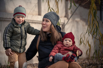Mamá con sus hijos bebé y niño disfrutando del otoño invierno entre los árboles