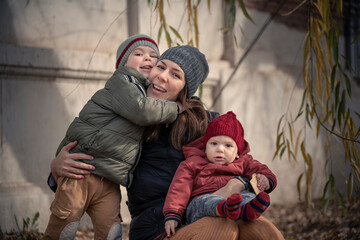 Mamá con sus hijos bebé y niño disfrutando del otoño invierno entre los árboles