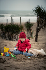Niño jugando con juguetes en la playa en otoño invierno
