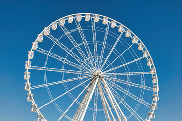 Big, tall white Ferris wheel in front of a perfect blue sky at the oceanfront in Marseille, France....