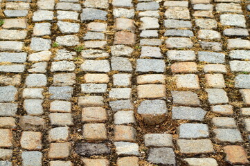 paving stones of rectangular and square stones of different colors and sizes. One stone is missing from the cobblestone road.