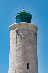 Fototapeta na wymiar Small stone-made lighthouse at the harbourfront of Cassis, France in front of a clear blue sky on a summer day. Vacation destination on the Côte d Azur.