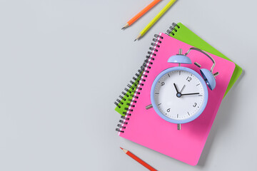 Colorful school supplies and alarm clock on blue background. Top view, flat lay.