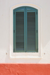 A window in an old building with green shutters. Green closed shutters. Minorca, Spain