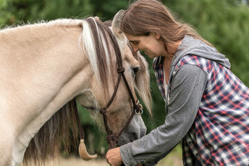 Portrait of a female equestrian interacting with her horse; paddock scenery