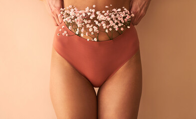 Cropped image of woman in lingerie with flowers made of panties on beige background. - obrazy, fototapety, plakaty