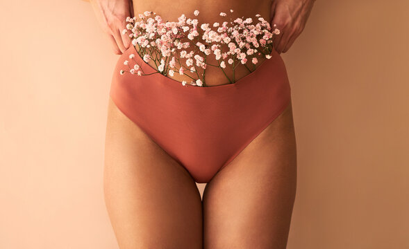 Cropped image of woman in lingerie with flowers made of panties on beige background.
