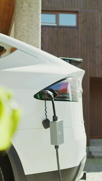 A electric car with a power cable connected to a charger stands in the backyard