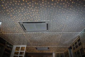 Decorative lighting with small round light bulbs attached to the ceiling as a decoration - obrazy, fototapety, plakaty