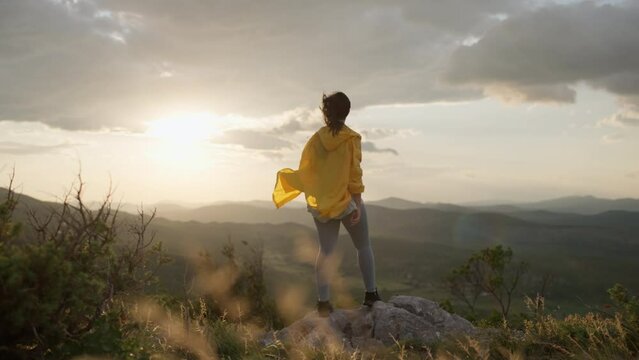 The girl runs to the top of the mountain and feels freedom. Mountain landscape at sunset and a woman conquers the mountains on a hike. High quality 4k footage