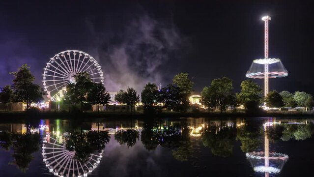 Fair at night reflecting in a river with some clouds time lapse