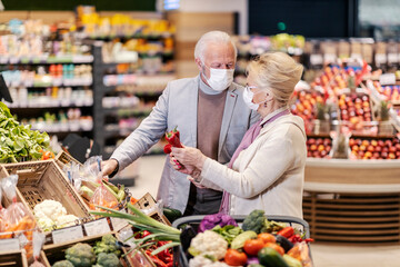 A senior couple buying fresh vegetables at the supermarket during corona virus.