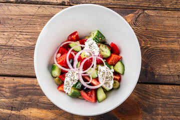 Greek salad of fresh cucumber, tomatoes, sweet pepper, lettuce, red onion, feta cheese and olives with olive oil. Healthy eating, top view
