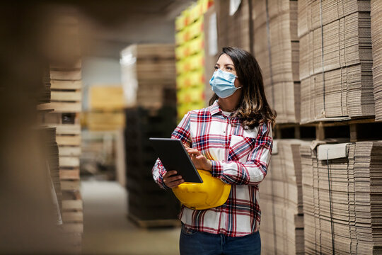 A paper industry manager with tablet in hands inventorying in warehouse.