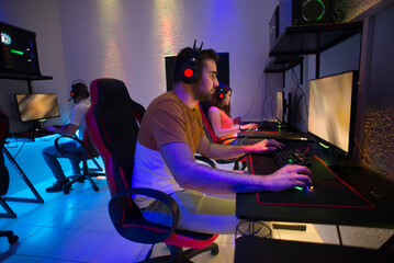 Team of gamers playing computer games at night
