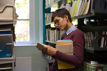 Young woman student reads books and study in the library