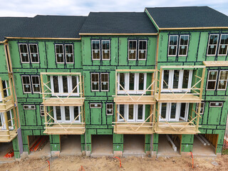 wooden frame of a three-story house sheathed with insulation panels. Construction site of a residential complex in Leesburg.